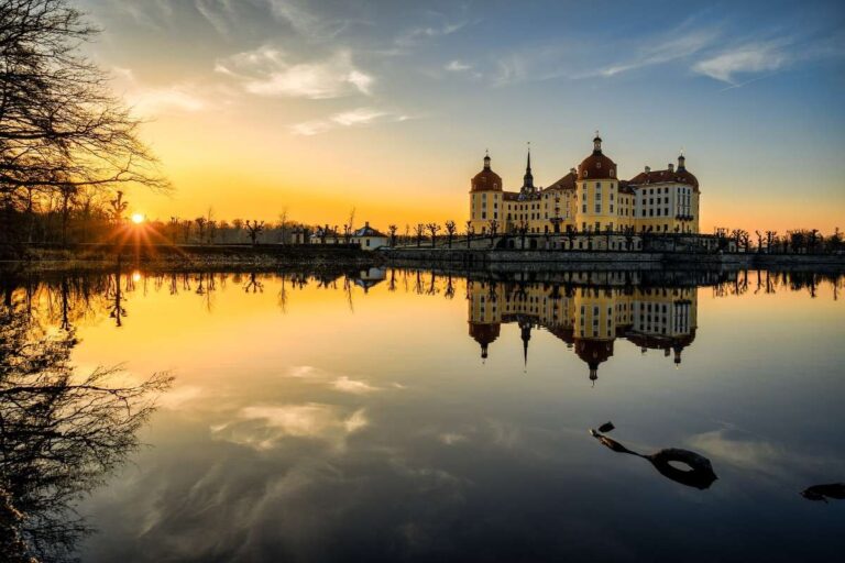 Sunset reflection of a castle on a lake with a silhouette of trees