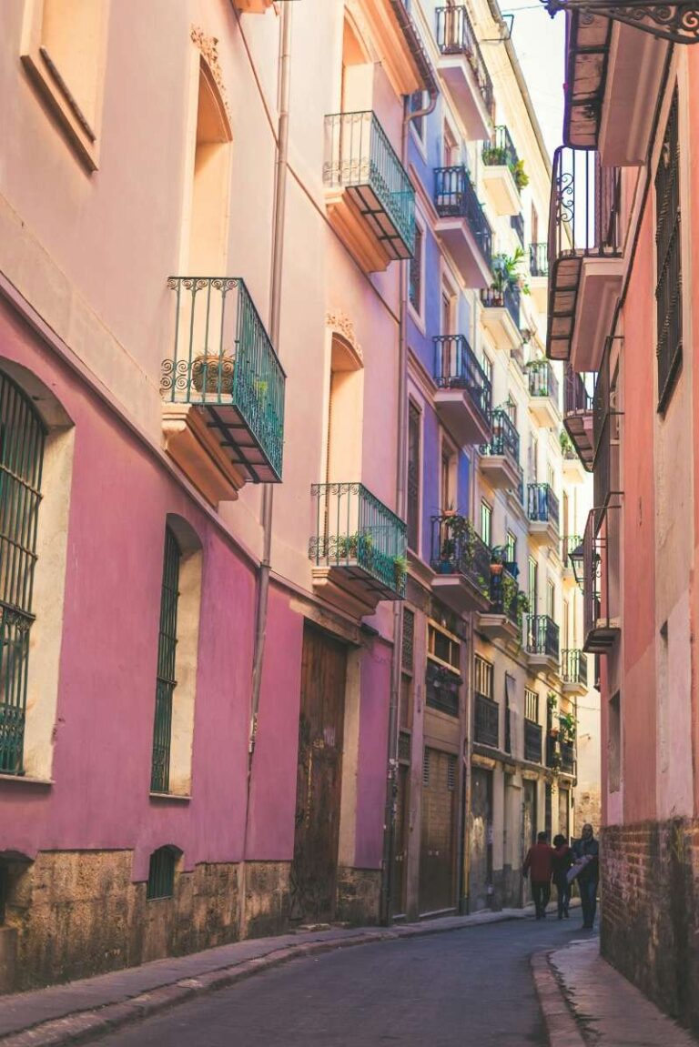 A narrow street with buildings and people in the old town of Valencia