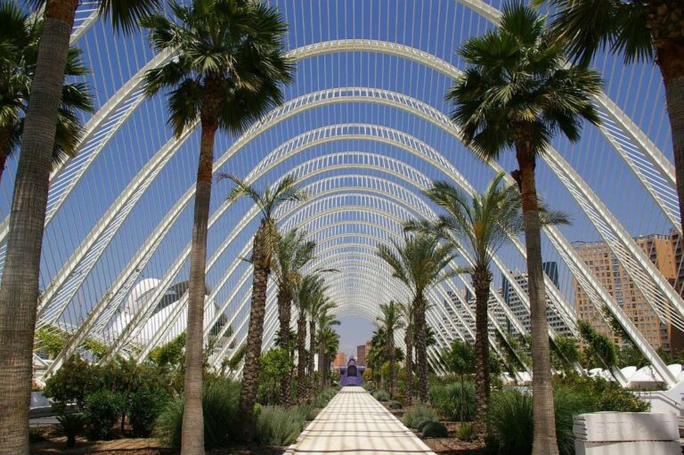 Pathway through a futuristic garden with palm trees and white arches in Valencia