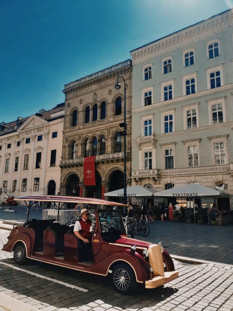 Vintage car in Vienna's center square under a clear blue sky