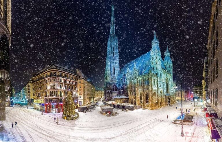 Snowfall at Vienna's Christmas market with a lit-up cathedral