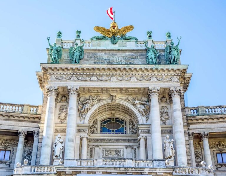 a traditional building with statues on top in Vienna called Hofburg palace