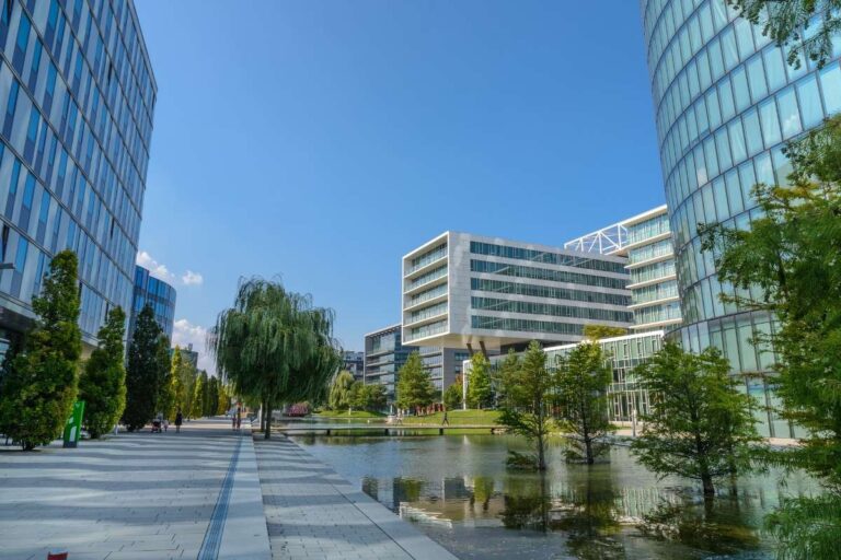 Modern glass buildings by a park and pond in Vienna on a sunny day