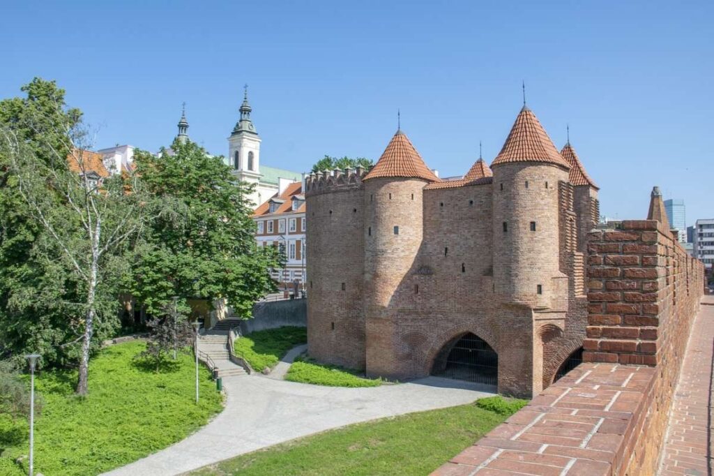 Historic Warsaw Barbican with towers and brick walls under a blue sky