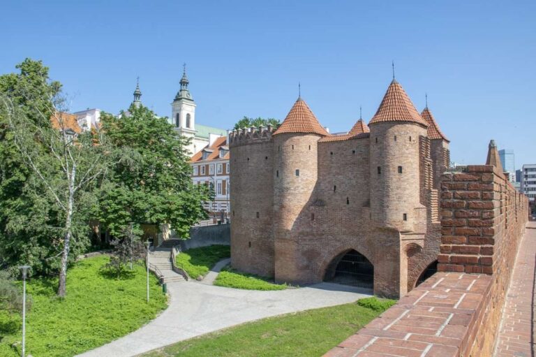 Historic Warsaw Barbican with towers and brick walls under a blue sky