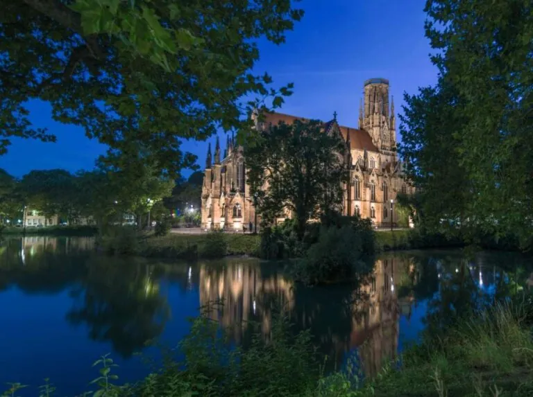 Illuminated church in Stuttgart at night, reflecting in a calm lake