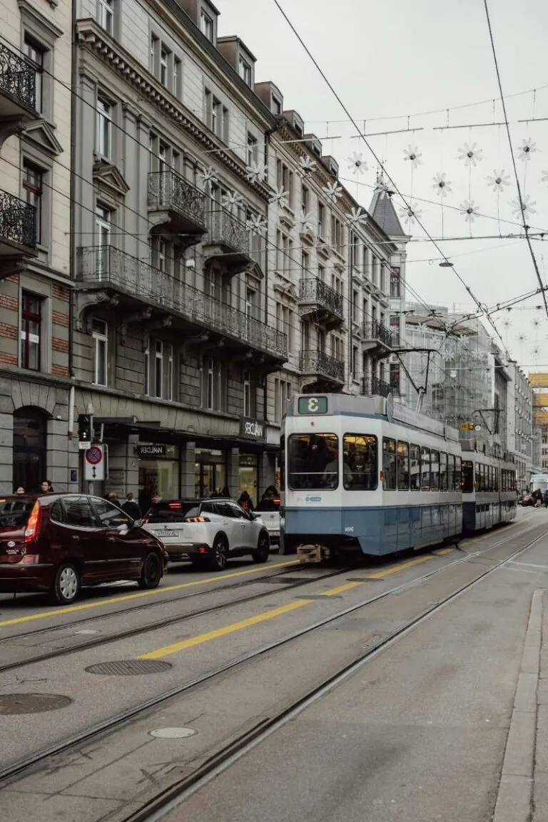 Tram and cars on a bustling street lined with historic buildings in Zurich