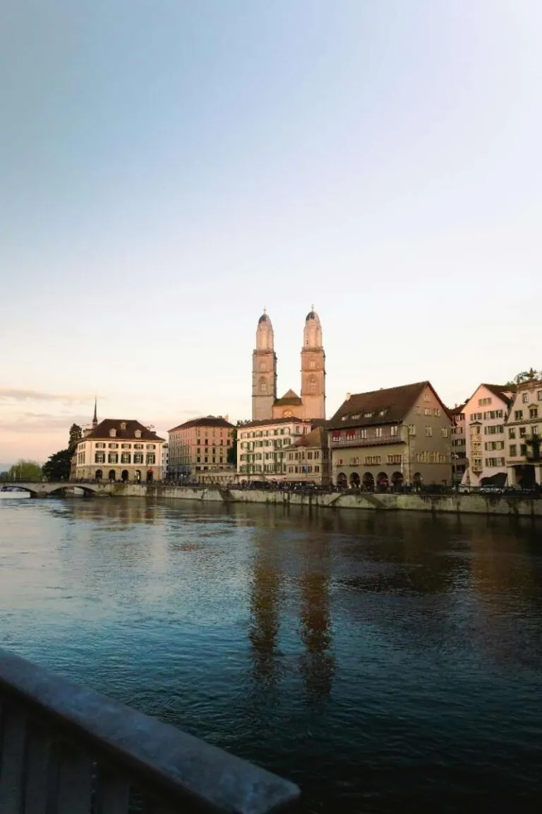 Church and historic buildings along the riverbank in Zurich at sunset