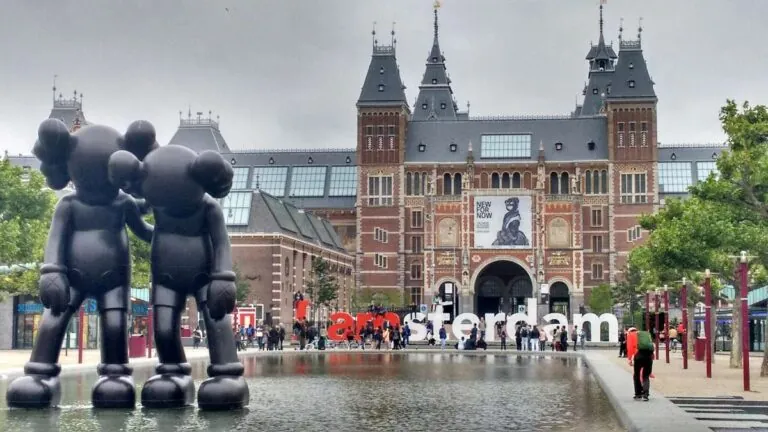 Rijksmuseum building in Amsterdam with large sculptures and a reflecting pool