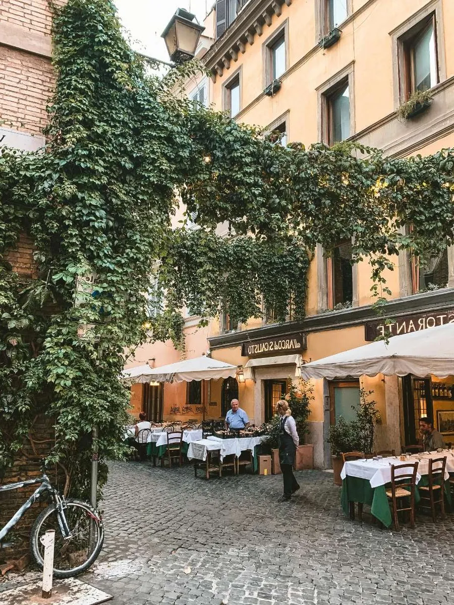 A charming Roman square with ivy-covered buildings and outdoor dining tables